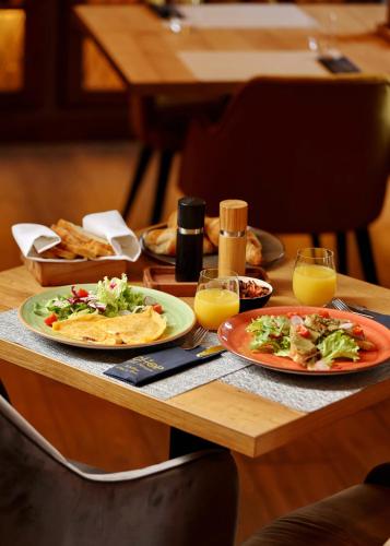 a table with plates of food and glasses of orange juice at Chop Old House Hotel in Velika Gorica