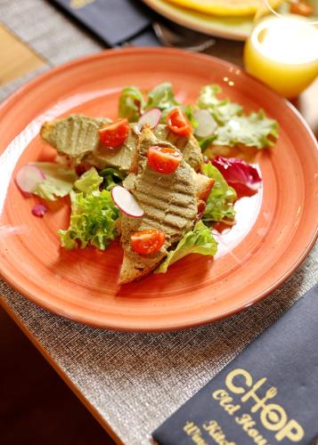 a orange plate of food with a salad on it at Chop Old House Hotel in Velika Gorica