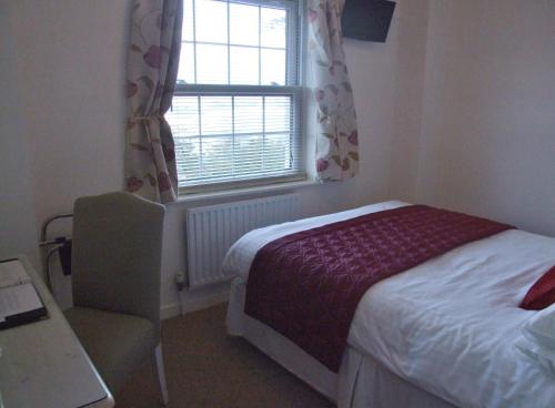 a bedroom with a bed and a window and a chair at Les Cotils in Saint Peter Port
