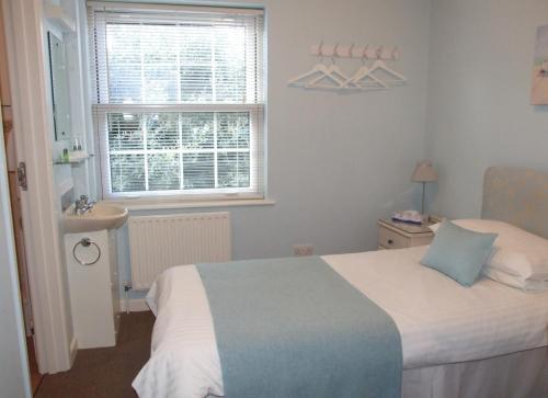 a small bedroom with a bed and a window at Les Cotils in Saint Peter Port