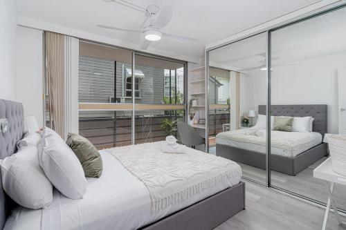 a bedroom with two beds and a glass wall at Fresh 2BD Koala Condo West End in Brisbane
