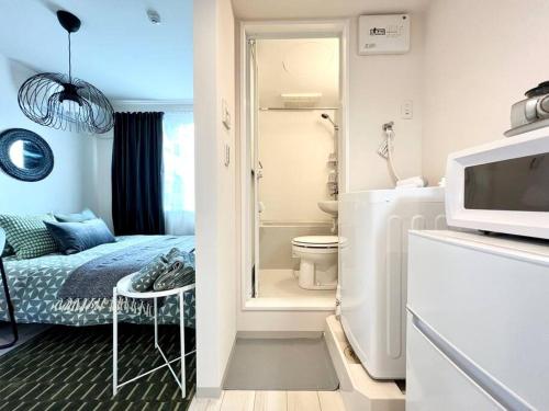 Habitación pequeña con baño con cama y microondas. en TYO Ikebukuro Designer’s Apt 202, en Tokio