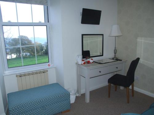 a bedroom with a desk and a mirror and a chair at Les Cotils in Saint Peter Port