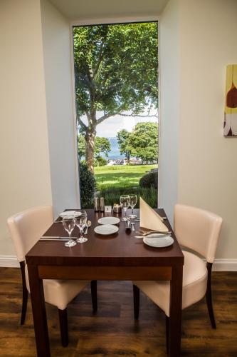 a dining room table with white chairs and a large window at Les Cotils in Saint Peter Port