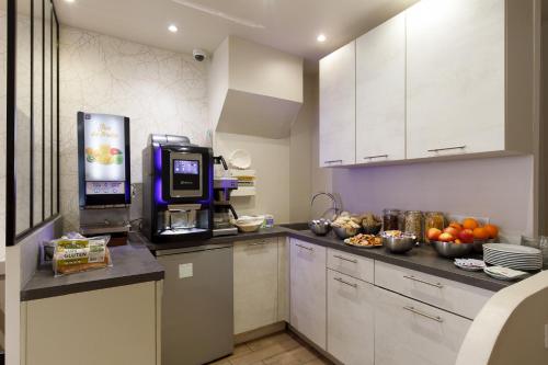 a kitchen with a coffee machine and fruit on the counter at Hôtel de l'Étoile in Antibes