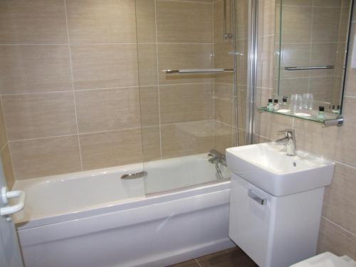 a bathroom with a tub and a sink and a shower at Les Cotils in Saint Peter Port