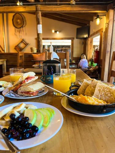 a table with two plates of breakfast foods and orange juice at Las Bravas Lodge in Las Trancas