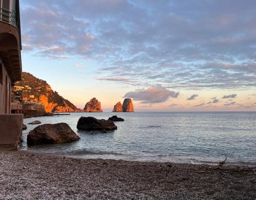 a beach with rocks in the water and a building at Capri Suite on the beach in Capri
