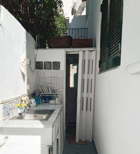 a white kitchen with a sink and a door at Capri Suite on the beach in Capri