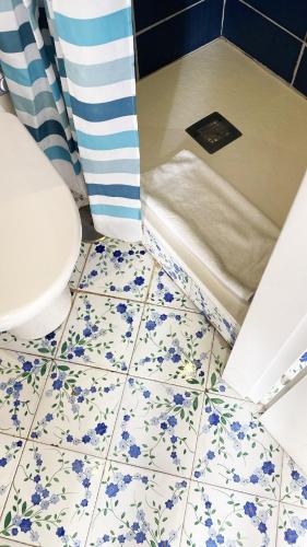 a bathroom with a toilet and blue flowers on the floor at Capri Suite on the beach in Capri