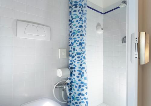 a bathroom with a blue shower curtain and a toilet at Hotel Baltic in Rimini