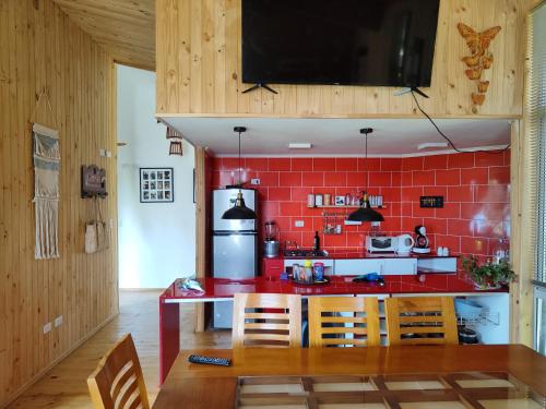 Cabaña familiar frutilar في Casma: مطبخ بجدار احمر وقمة رد