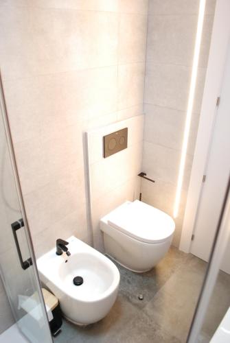a bathroom with a white toilet and a sink at Altar Suites Caño Badillo by gaiarooms in León