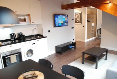 a kitchen and living room with a table and a tv at Altar Suites Caño Badillo by gaiarooms in León