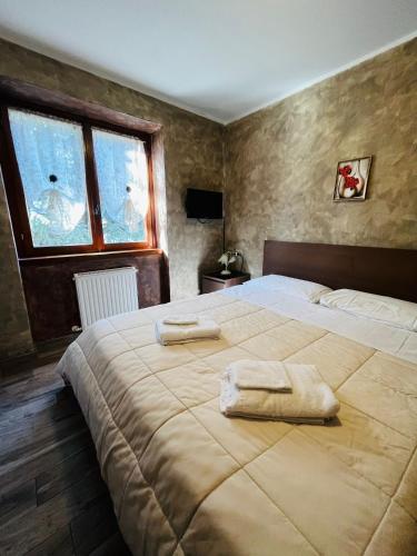 a bedroom with a large bed with towels on it at San Luigi - Rooms & Apartments in Campodolcino