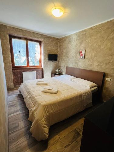 a bedroom with a large bed with two towels on it at San Luigi - Rooms & Apartments in Campodolcino