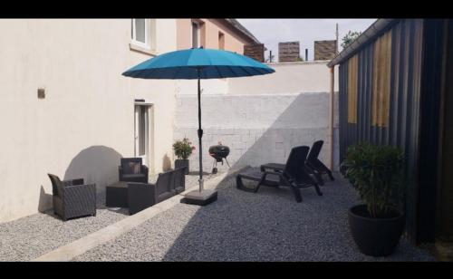 un patio con sillas y una sombrilla azul en Ile de Saint-Nicolas T2 et/ou Ile de Penfret Studio, en Fouesnant