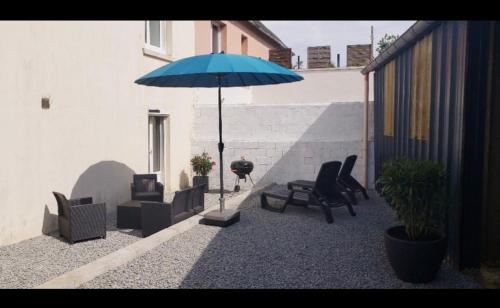 Ile de Saint-Nicolas T2 et/ou Ile de Penfret Studio في فوسنان: فناء به كراسي ومظلة زرقاء