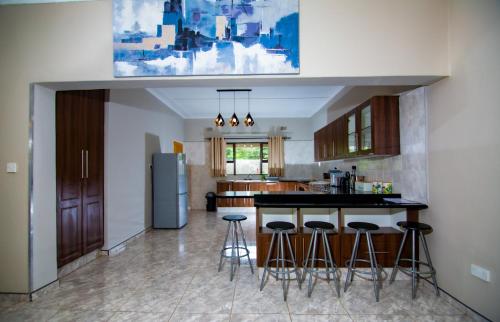 a kitchen with a bar with stools and a refrigerator at Dzimbahwe Guest Lodge in Victoria Falls