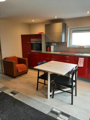 a kitchen with red cabinets and a table and chairs at Appartement Oase in Klimmen