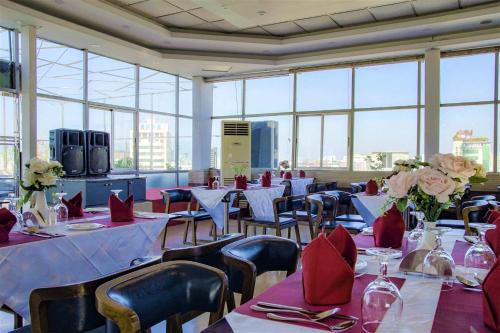 uma sala de jantar com mesas e cadeiras com guardanapos vermelhos em Hotel Shuktara Dhaka em Daca