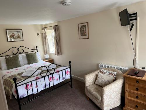 a bedroom with a bed and a chair at The Coppleridge Inn in Motcombe