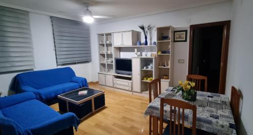 Apartamento Plasencia Illuminati في بلاسينثيا: غرفة معيشة مع أريكة زرقاء وطاولة