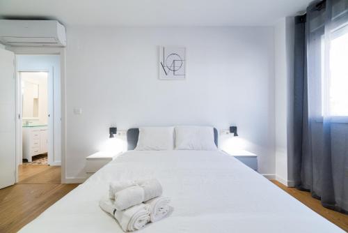 a bedroom with a white bed with towels on it at Piso en Palacio Quinta Alegre in Granada