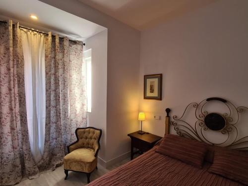 a bedroom with a bed and a chair and a window at 1930 Diecinueve Treinta "Diseño, historia y confort en el centro de Gijón" in Gijón