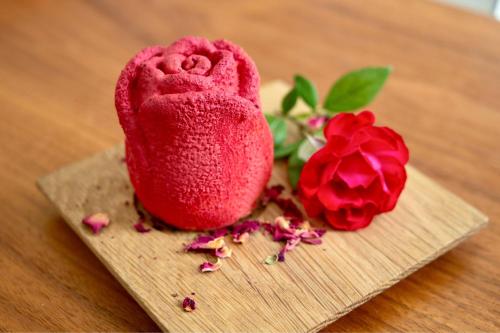 a red cookie sitting on a cutting board next to two roses at JW Marriott Venice Resort & Spa in Venice