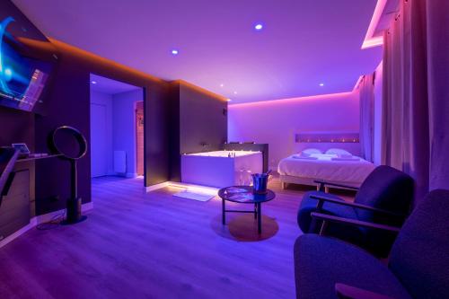 a bedroom with a bed and a room with purple lights at LA BULLE DÉTENTE / BALNÉO - SAUNA in La Riche