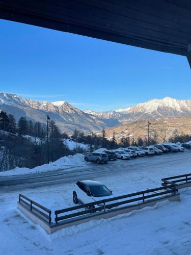 une voiture garée dans un parking dans la neige dans l'établissement SUPER SAUZE Studio pied des pistes, à Enchastrayes