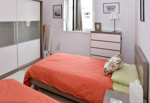 1 dormitorio con 1 cama con sábanas de color naranja y espejo en Valley of Honey Apartment en Mosta