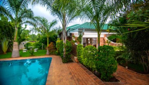 a house with a swimming pool and palm trees at Dzimbahwe Guest Lodge in Victoria Falls