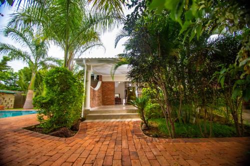 a brick walkway in front of a house with trees at Dzimbahwe Guest Lodge in Victoria Falls