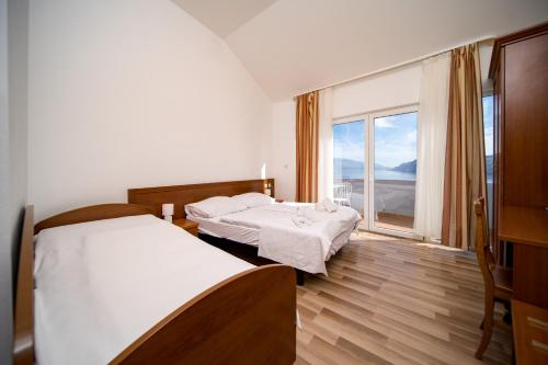 2 camas en una habitación con ventana grande en Pansion Lavanda Lopar en Lopar