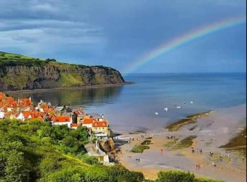 a group of people on a beach with a rainbow at Falconhurst in Robin Hood's Bay