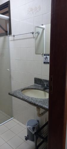 uma casa de banho com um lavatório e uma lata de lixo em Apartamento Climatizado a 150 Metros da Praia em Ubatuba