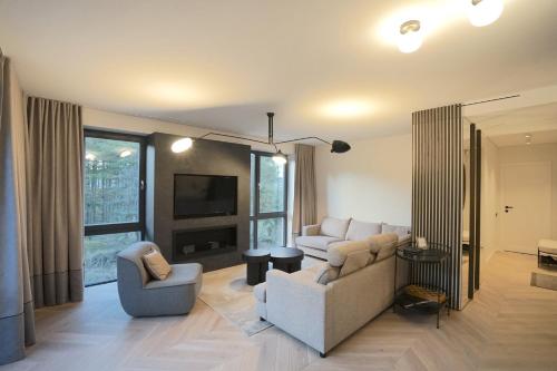 ein Wohnzimmer mit einem Sofa, 2 Stühlen und einem TV in der Unterkunft A T Ò K V Ė P I S in Nida