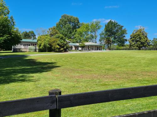 a wooden fence in front of a field with a house at The Olde Store - Hunua Holiday Home in Hunua