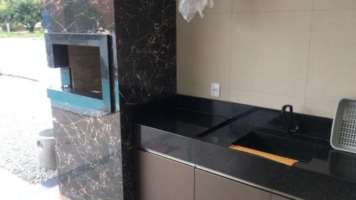 a kitchen with a black counter top and a sink at Casa de Praia, pé na areia Guaratiba Prado - Bahia in Prado