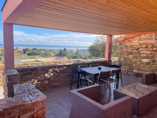 een patio met een tafel en stoelen en een stenen muur bij La Bergerie Furiani avec piscine privée Residence Digoune in Furiani