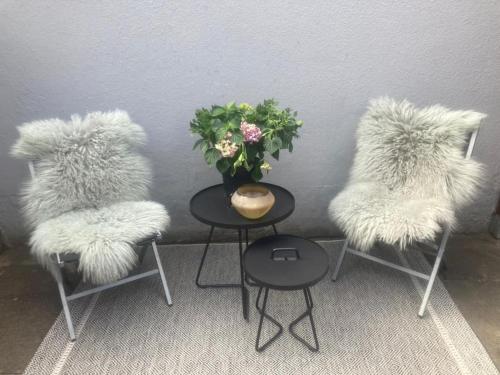 3 Stühle mit pelzigen Sitzen und einem Tisch mit Vase in der Unterkunft Modernes, familienfreundliches Apartment in Lübeck in Lübeck