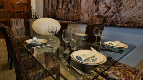 a glass table with plates and wine glasses on it at La Sinagoga in Peñaranda de Duero