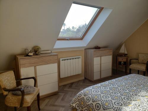 1 dormitorio en el ático con cama y ventana en Ile Cigogne, en Fouesnant