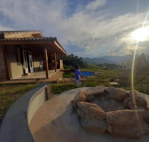 a child standing in front of a fire pit in front of a house at Cabana do Camelo in São Bento do Sapucaí