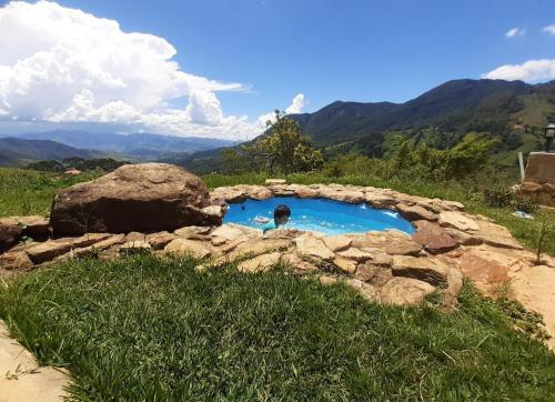 a person standing in a small pool in a field at Cabana do Camelo in São Bento do Sapucaí