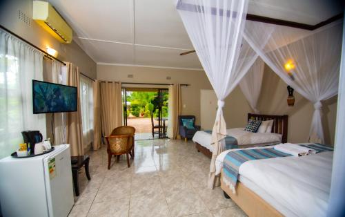 a bedroom with two beds and a living room at Dzimbahwe Guest Lodge in Victoria Falls