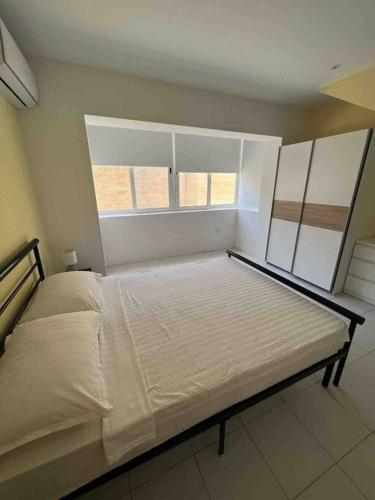 een groot bed in een kamer met een raam bij Brand new apartment in the heart of Saint Julians in Tal-Għoqod