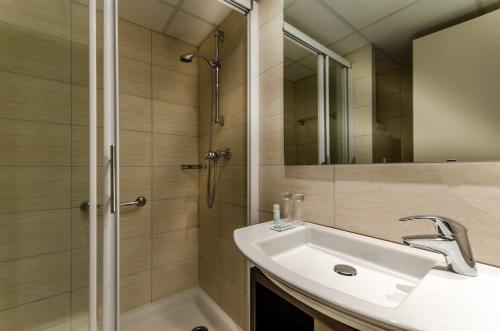 uma casa de banho com um lavatório e um chuveiro em Helgon Hotel - Lourdes Pyrénées em Lourdes